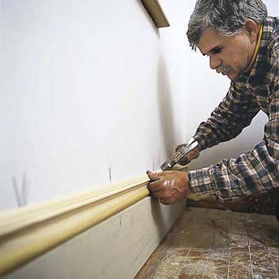 Man Nails On Cap Molding Of Baseboard